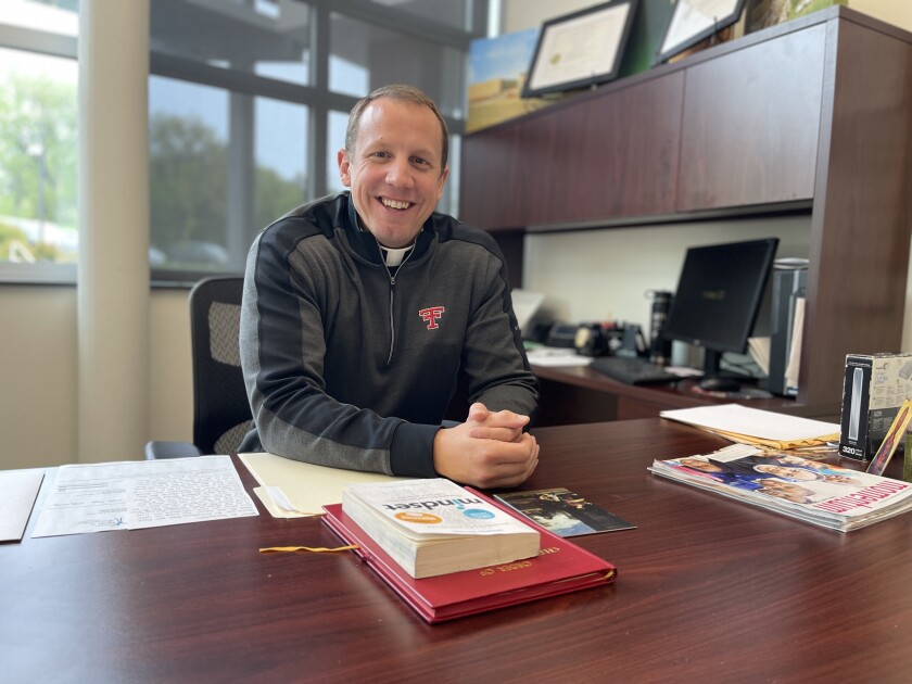 Father Kregg Hochhalter smiles at his desk Monday, June 6, 2022, at Trinity Catholic Schools.