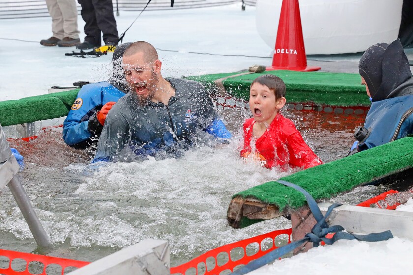 People jump into the water during the Polar Plunge event on Pelican Lake.