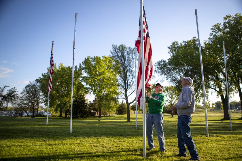 Gordon Keller, from left, and Wayne Emberland work together to raise an American flag at the Flags of Honor Memorial in Willmar on Friday, May 27, 2022.