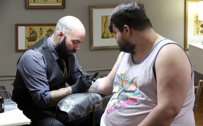 North Shore Tattoo Co. owner Jeremy Anderson tattoos Justin Swenson.