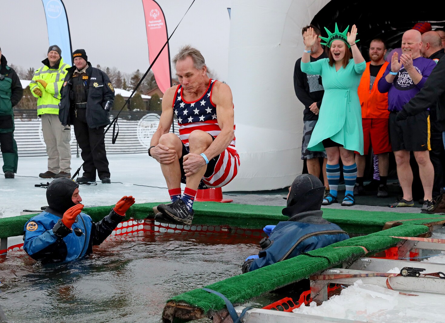 People jump into the water during the Polar Plunge event on Pelican Lake.