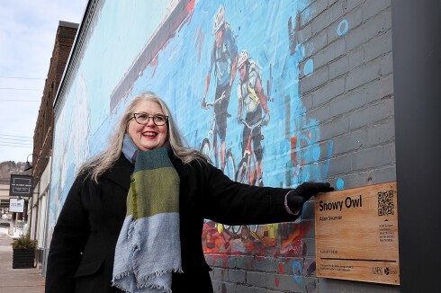 Woman stands by mural.