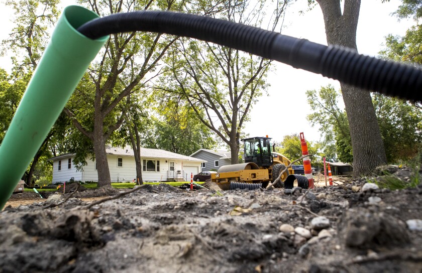 A worker uses a road roller to compact new road material deposited along 6th Street SW on Tuesday, August 16, 2022.