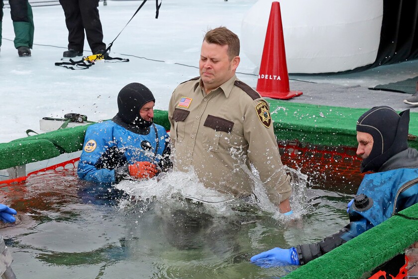 People jump into the water during the Polar Plunge event on Pelican Lake.