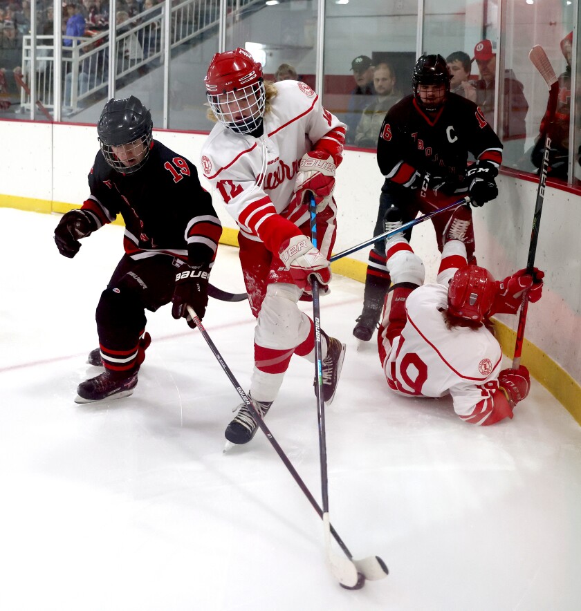 Worthington Trojans Alec Langgerud (19) battles for control of the puck with Luverne's Elliot Domagala (12) as Trojans Blake Luinenburg (16) and Cardinals Patrick Kroski untangle after bouncing off the boards during section 3A Tournament play Thursday night at the Blue Mound Ice Arena.