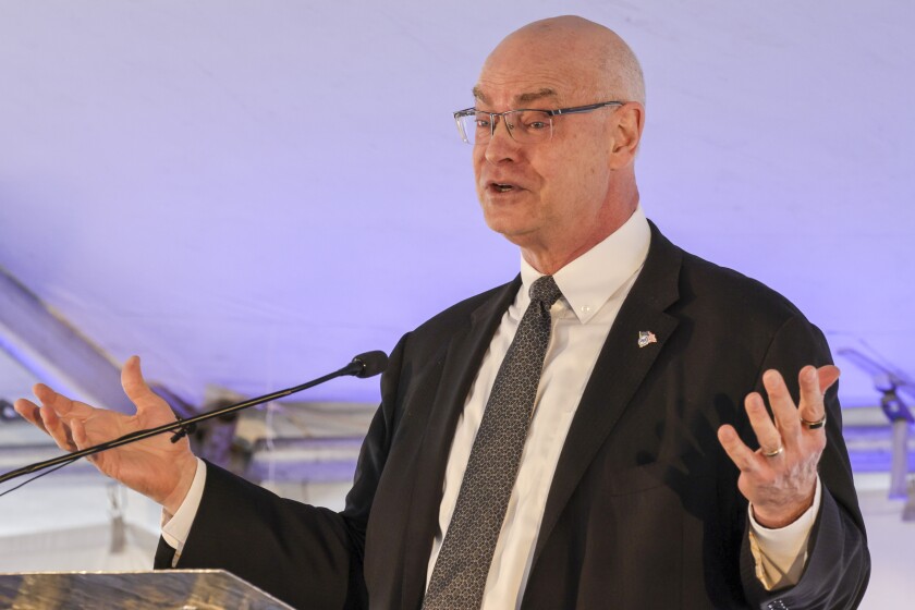 Man raises hands while speaking during event in Keewatin