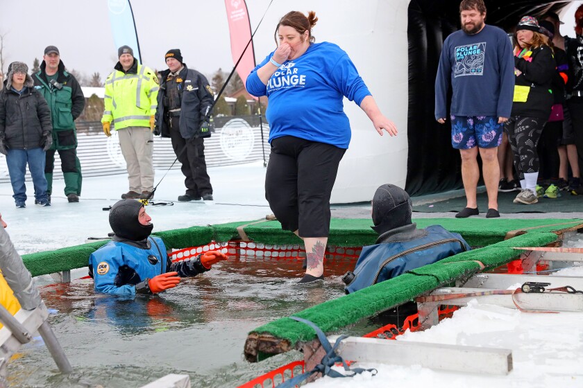 People jump into the water during the Polar Plunge event on Pelican Lake.