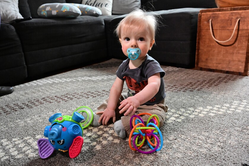 Baby sits on floor surrounded by toys