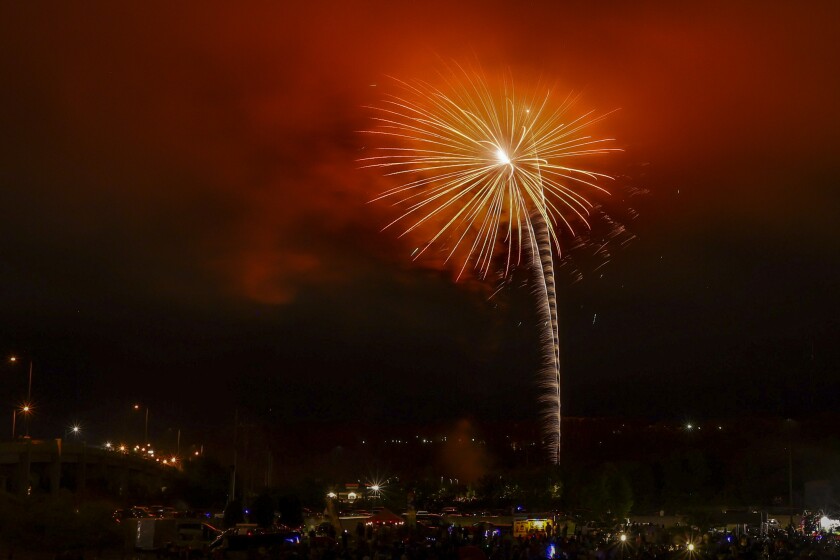 Large aerial fireworks burst in cloudy foggy night sky