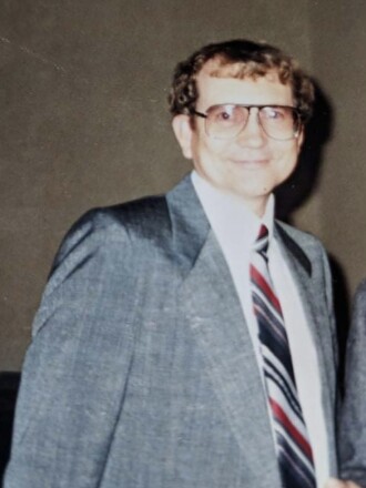 A smiling man in a suit poses for a photo