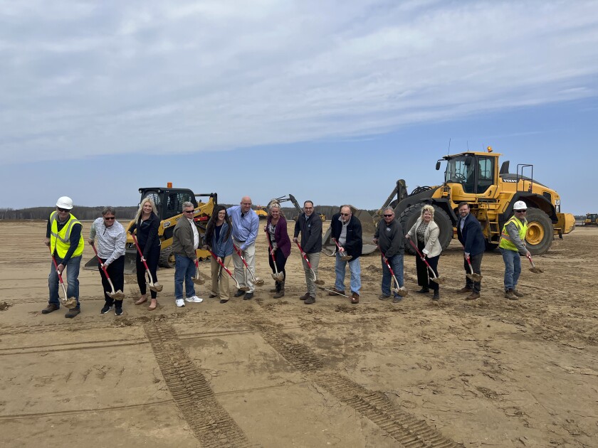 A line of people stand holding shovels