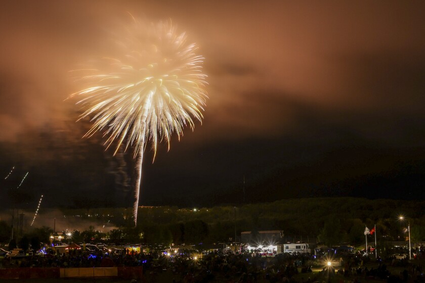 Large aerial fireworks burst in cloudy foggy night sky