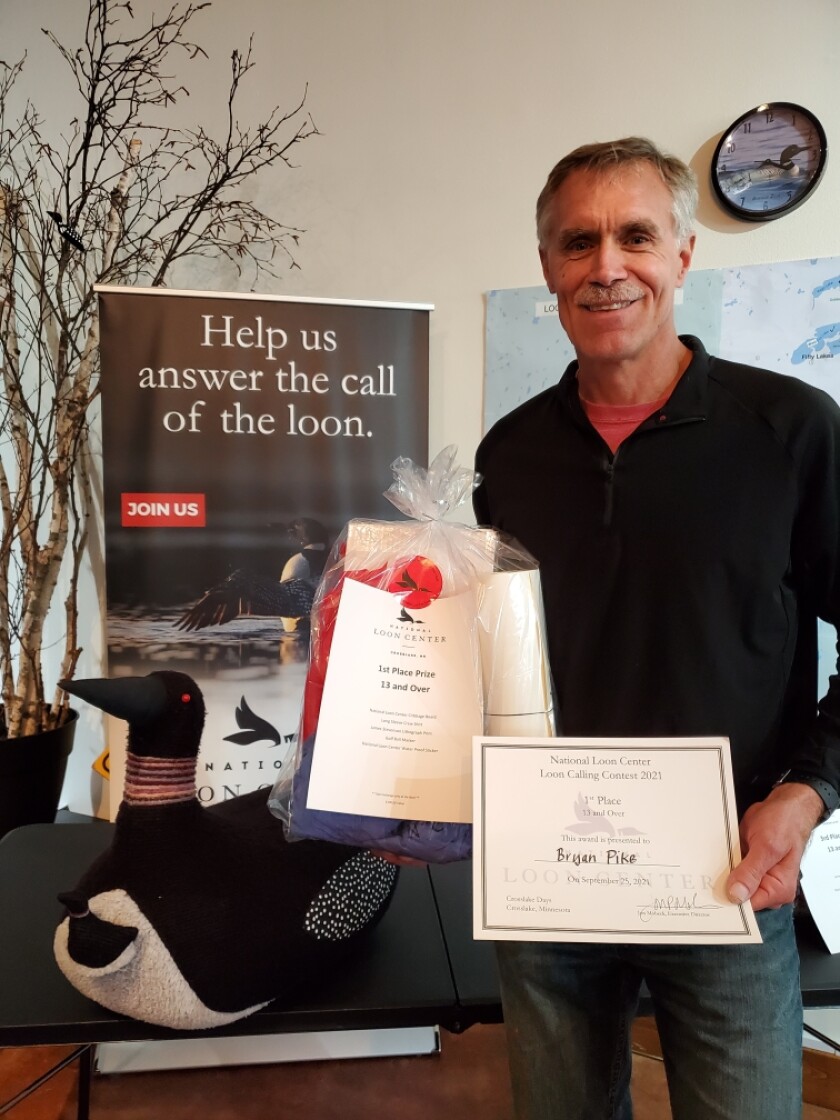Bryan Pike holds a gift bag and an award certificate as the first-place winner in the adult age category of the 2021 National Loon Center Loon Calling Contest in Crosslake.