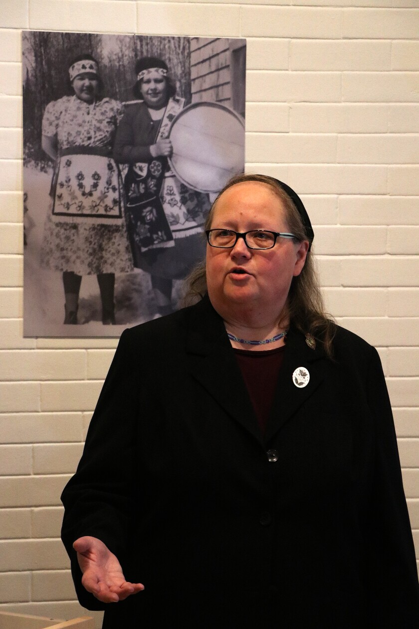 Woman talks in front of old picture on the wall.
