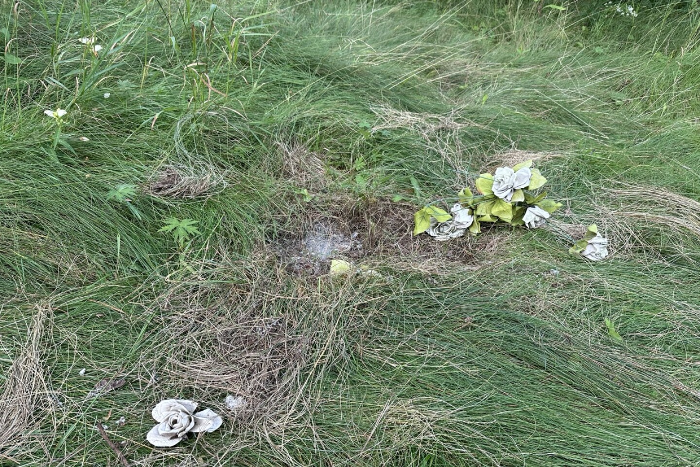 Artificial flowers sit near a buried headstone