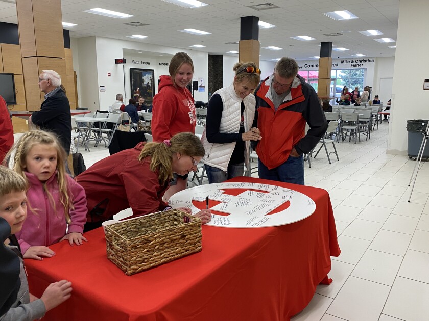 Students and community members sign a farewell Titan emblem for Father Kregg Hochhalter during his goodbye party Monday, June 6, 2022, at Trinity Catholic Schools.