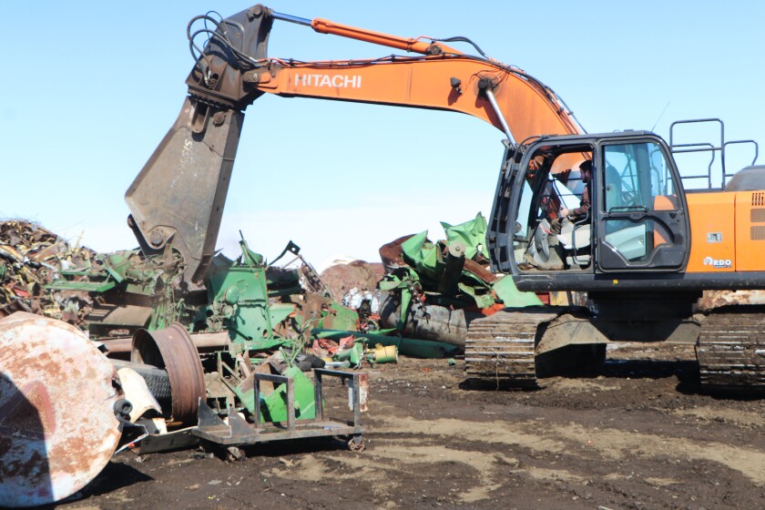A yellow, tracked "shear" machine chews up a 1970s-era John Deere combine in a matter of minutes.