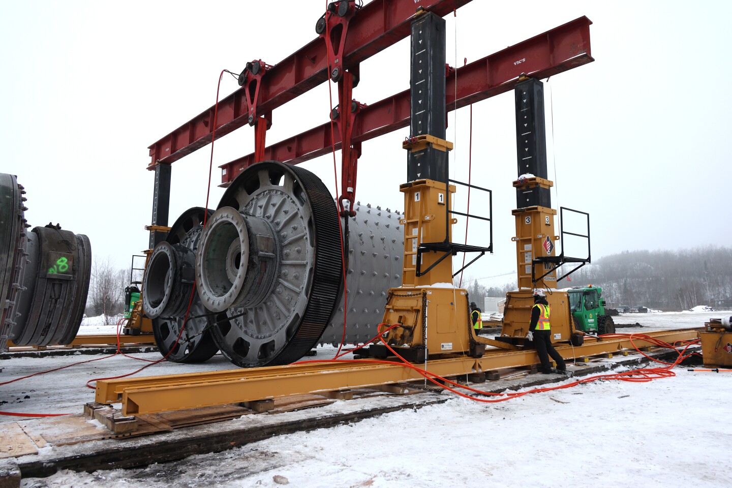 Grinding mill is lowered to ground with gantry crane in salvage yard