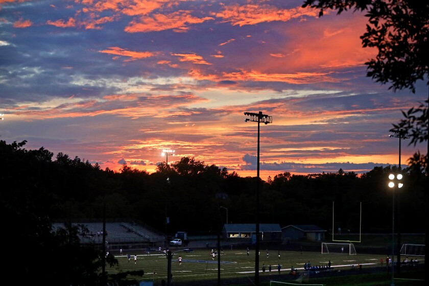 Sunset in Brainerd, the Brainerd High school field with soccer players on it.