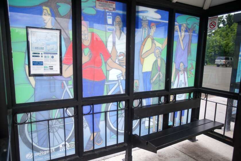 A bus shelter with a mural showing a summer scene.