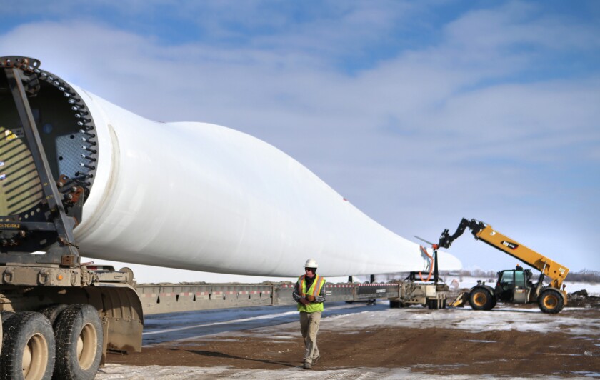 Jeff Thornton, a truck driver for Global Specialized Services, inspects a 25,000-pound wind turbine blade that is loaded off a semi Friday at a railyard north of Grand Forks. The blade is one of dozens waiting to be shipped by rail to Kansas, where customers hope to build wind farms. photo by Eric Hylden/Grand Forks Herald