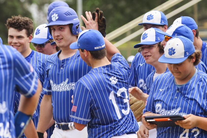 High school baseball players play on outdoor field on sunny day