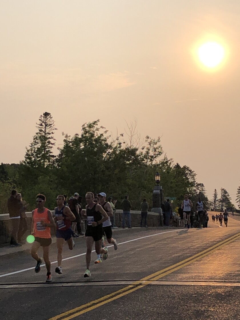 Runners on asphalt highway with orange haze in sky