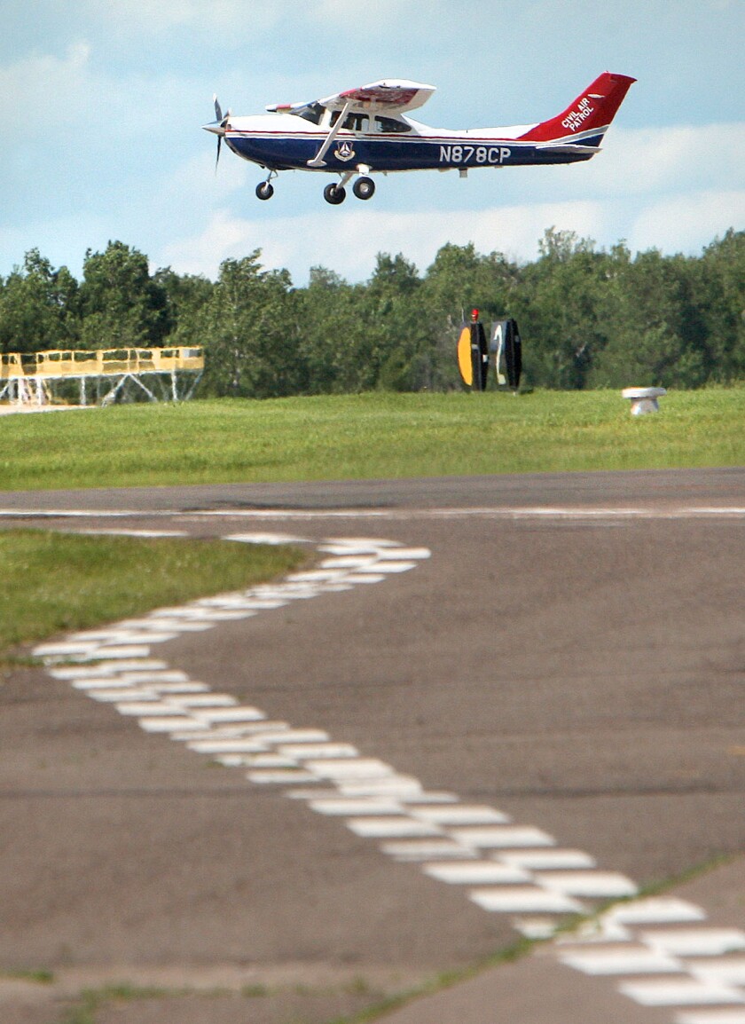 A small plane flies over a runway