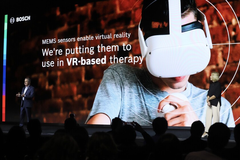 People present on stage with a large background showing a person using virtual reality goggles.