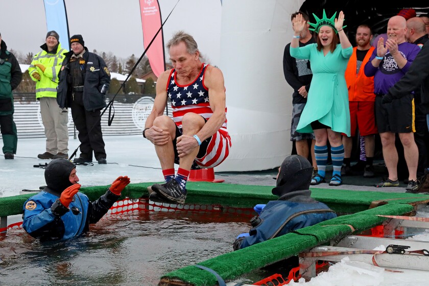 People jump into the water during the Polar Plunge event on Pelican Lake.