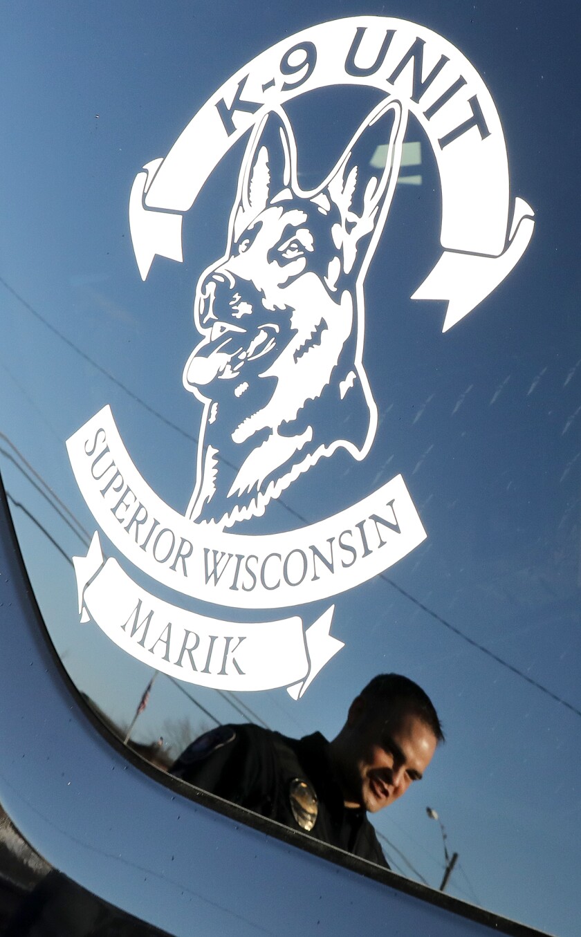 Sgt. Nick Eastman is reflected in the window of his vehicle next to K-9 Marik’s decal
