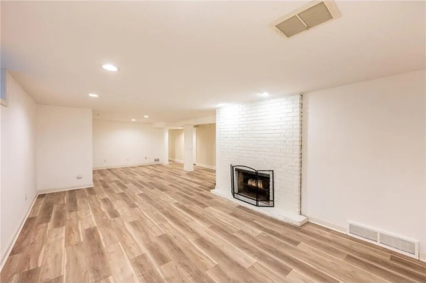 A white brick fireplace and tan floors in a home's basement.