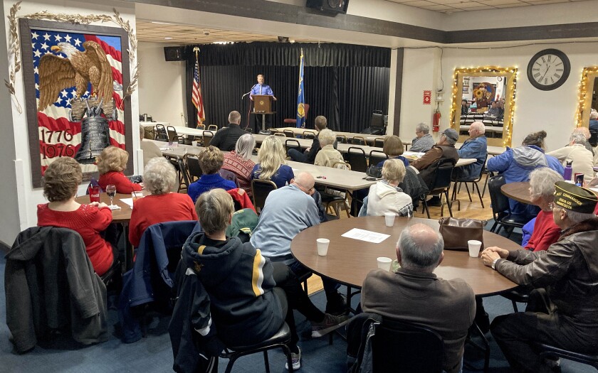 People sitting at tables and listening to a speech during a Veterans Day event.
