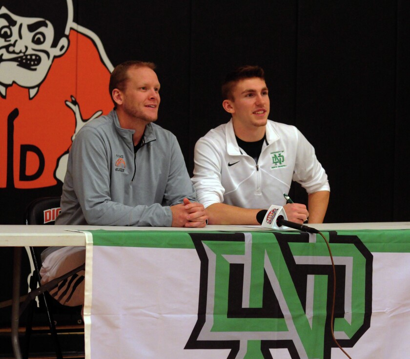 Dickinson High senior Aanen Moody, right, signs his National Letter of Intent on Wednesday to play men's basketball at the University of North Dakota. With him is Midgets basketball coach Dan Glasser. (Parker Cotton / The Dickinson Press)