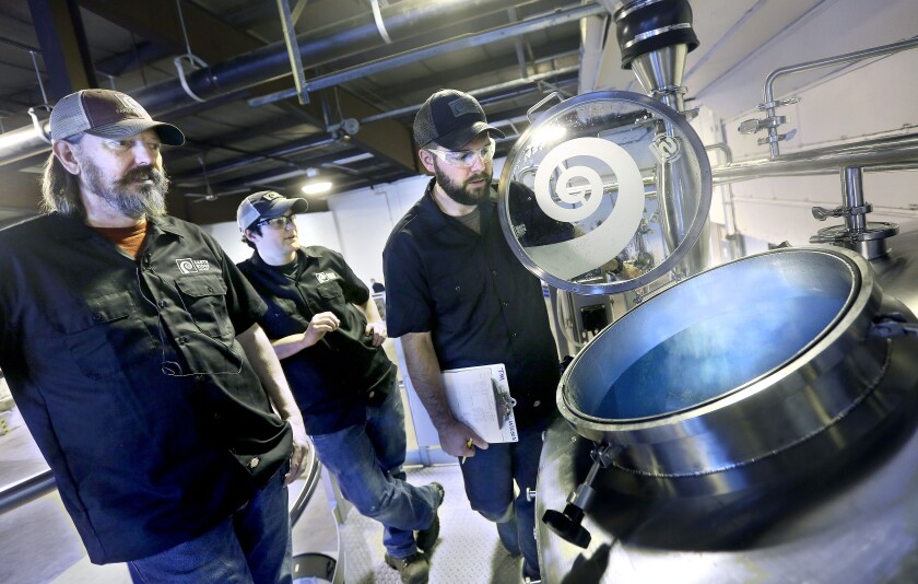 Steam rises from a large tank called a mash tun as Tim Nelson, founder of Earth Rider Brewery (left), along with co-lead brewers Allyson Rolph and Tim Wilson, check the progress of the steeping of the malts while making one of their first batches of wheat beer at the Earth Rider Brewery in Superior Thursday morning. Bob King / rking@duluthnews.com