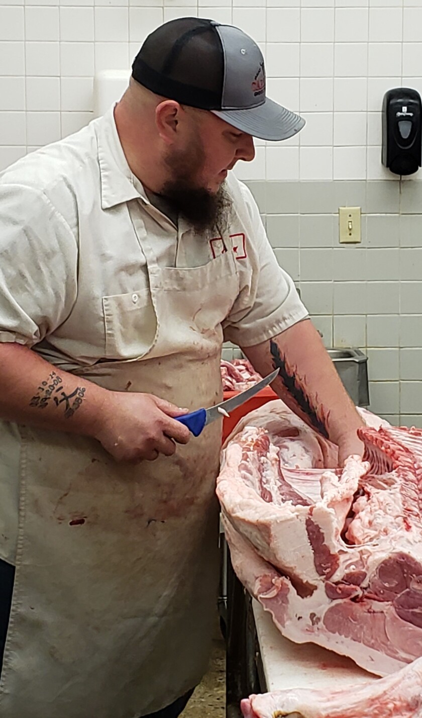 Man in butcher shop cutting pork