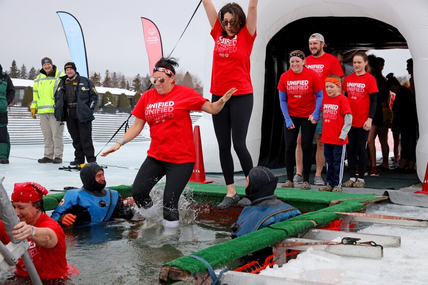 People jump into the water during the Polar Plunge event on Pelican Lake.