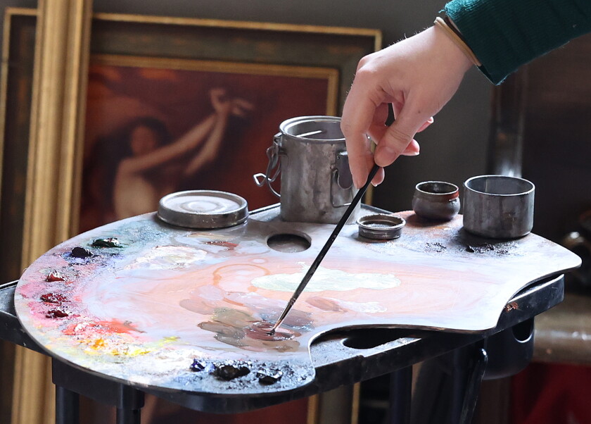 Artist mixes paint on a pallet.