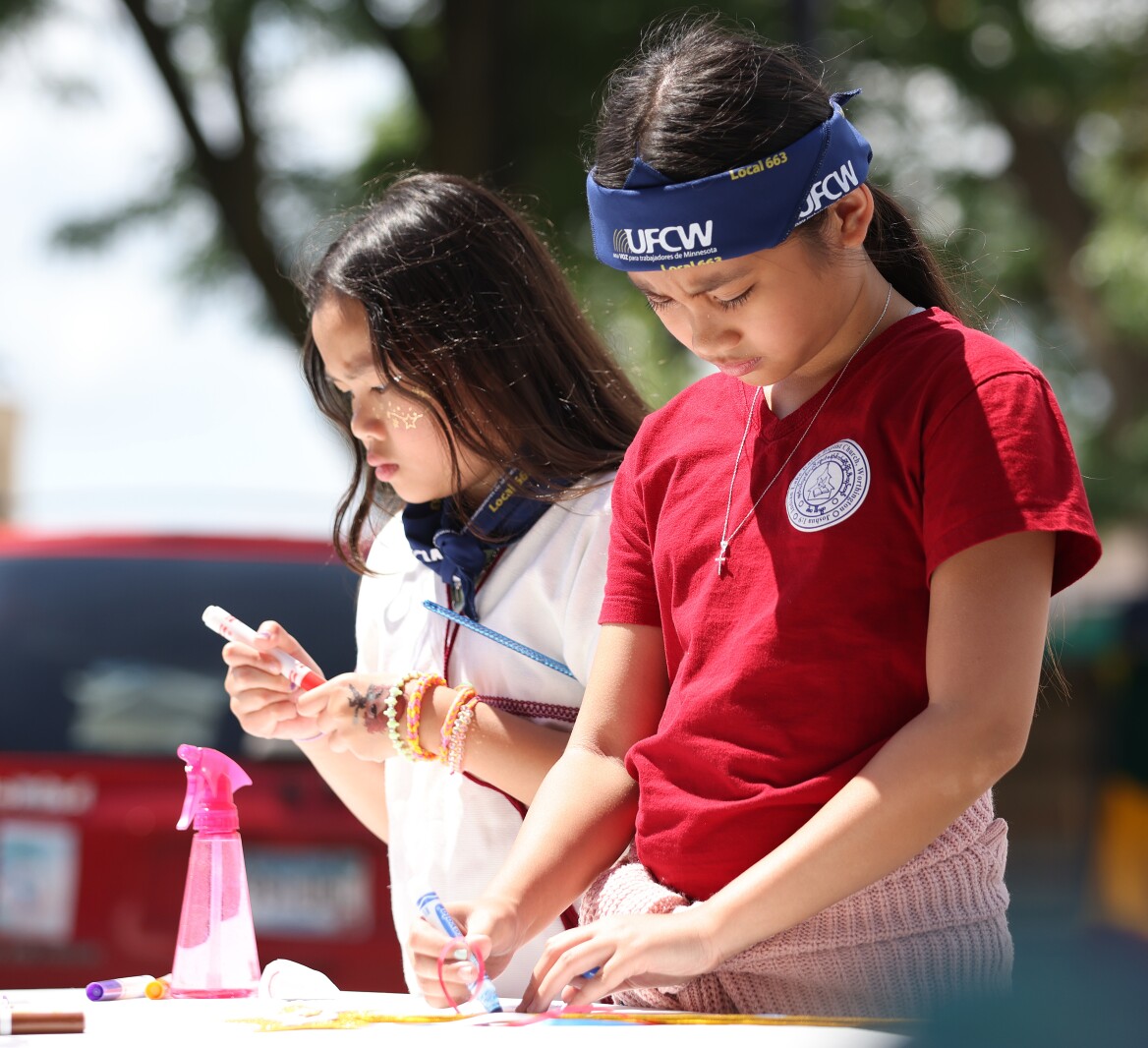 Girls make pendants at the ArtMobile on 10th Street during the International Festival on Saturday, July 9, 2022.