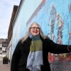 Woman stands by mural.