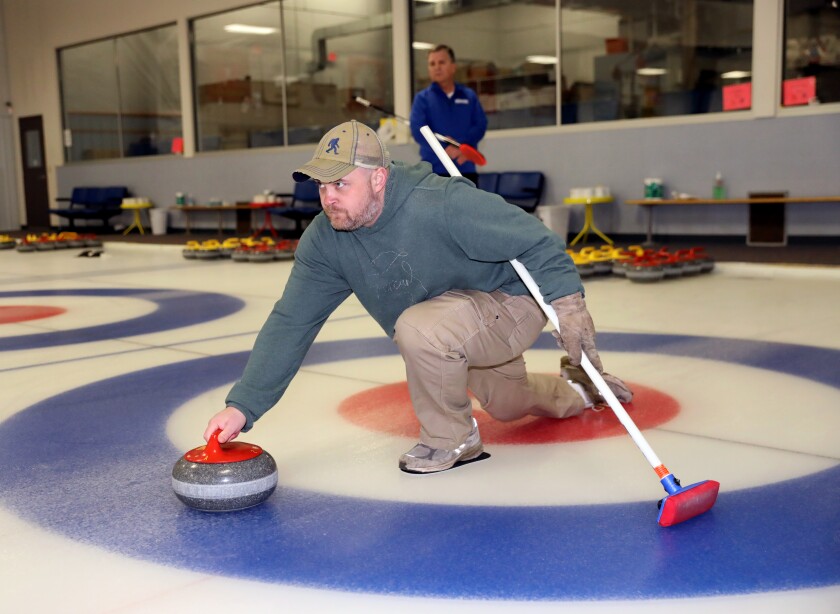 Tim Speier delivers a rock during a curling lesson.