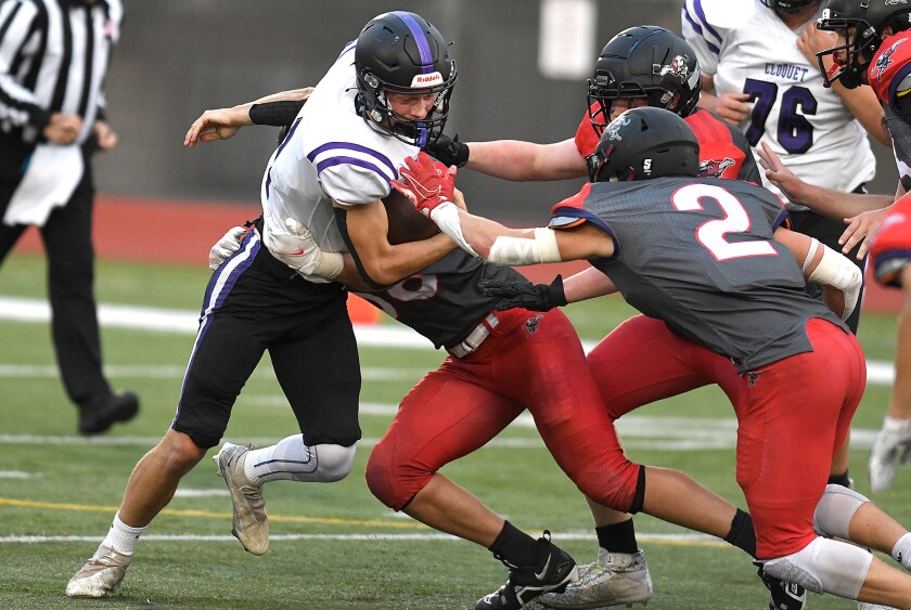 Cloquet quarterback Reese Sheldon (1) fights for extra yards as he gets wrapped up by the Duluth East defense