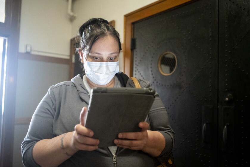 Navada Prigge fills out paperwork on an iPad before receiving free COVID-19 testing kits