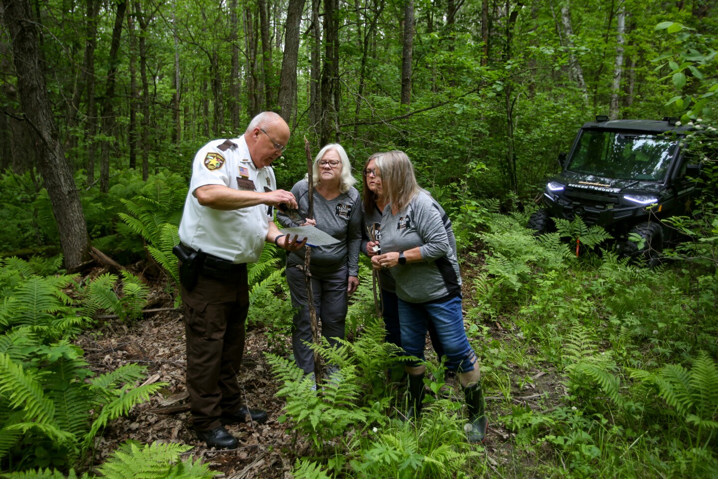 Becker County Sheriff Todd Glander shows sisters Lori Voigt, Jo Cornell, and Michelle Donahue a map of the area where their grandmother Milda McQuillan was last seen 50 years ago near Bad Medicine Lake in Northwestern Minnesota. The area they are standing in is where McQuillan's abandoned car was found near a swamp, one-third of a mile off Black Bear Beach Road.