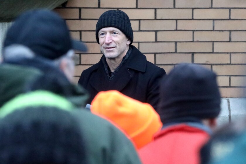 A man standing behind a crowd at a ceremony.