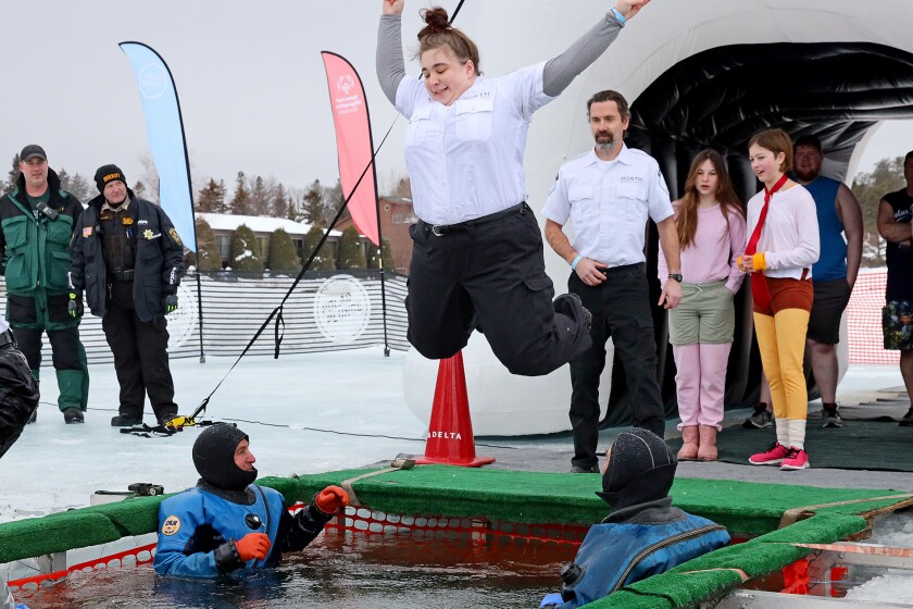 People jump into the water during the Polar Plunge event on Pelican Lake.