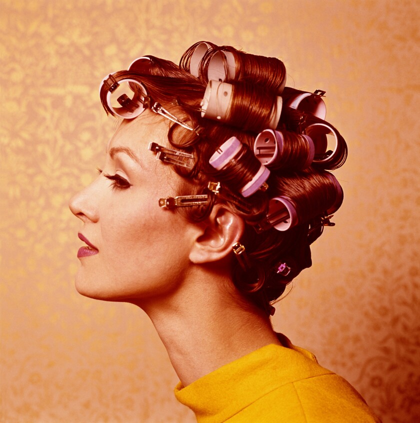side profile of light-skinned woman with brown hair wound into pink cylinder rollers