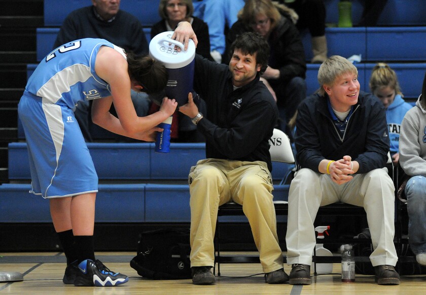 Superior trainer Mike Gogolin, center, holds up a cooler for a Spartan basketball player