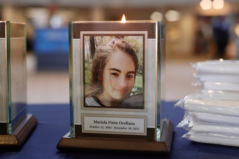 A plaque and candle with a portrait of Mariela Pinto Orellana.