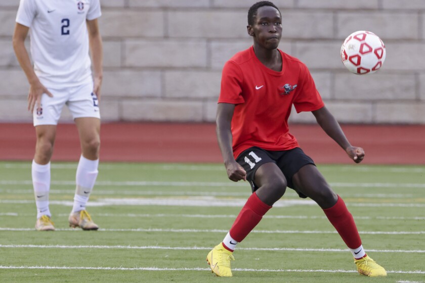High school boys soccer players in red uniforms playing players in white uniforms outdoors